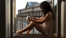 Картинка: Брюнетка в блузке сидит на окне со стеклянным шаром в руках.
