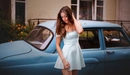 Image: A girl in a dress poses against the backdrop of a retro car.