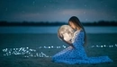 Картинка: Девушка в платье сидит на песке и держит в руках сферу похожую на луну