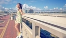 Image: A girl stands on a bridge with a beautiful view of the city.