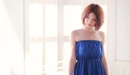 Картинка: Азиатка стоит в синем платье возле окна