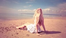 Картинка: Девушка в красивом платье сидит на берегу моря.