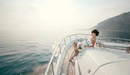 Картинка: Девушка с цветами на яхте смотрит на горизонт в море.