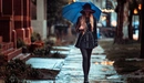 Картинка: Девушка в шляпе и плаще идёт под зонтом в дождливую погоду.
