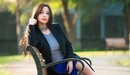 Картинка: Длинноволосая девушка сидит на скамейке в парке