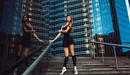 Картинка: Девушка - балерина позирует стоя на фоне высоко-этажных зданий.