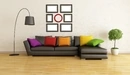 Image: Dark leather sofa with bright cushions.