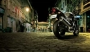 Картинка: Чёрный Suzuki стоит ночью на городской улице.