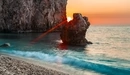 Картинка: Солнце садится за скалами, с видом на море.