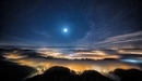 Image: The night sky above the town covered with fog