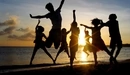 Картинка: Компания друзей веселятся на берегу моря при закате.