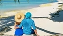 Картинка: Молодая пара сидит на пляже в тропиках любуясь на море.