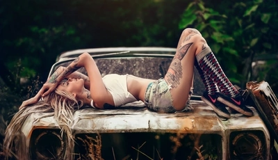 Image: Girl, blonde, tattoo, posing, lying, car, old, rusty, photo shoot, nature
