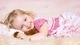 Картинка: Девочка лежит на мягком пледе обнявшись с игрушкой
