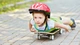 Image: The boy lying on his stomach riding on a skateboard