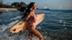 Картинка: Брюнетка с доской для сёрфинга бежит в море поплавать