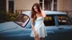 Image: A girl in a dress poses against the backdrop of a retro car