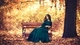 Картинка: Брюнетка в длинном платье сидит на скамейке в осеннем парке