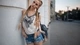 Картинка: Блондинка с длинными косичками в джинсовых шортах