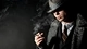 Image: Man in coat and hat smoking a cigar