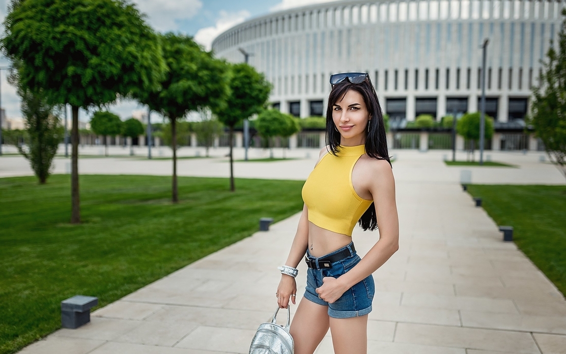 Image: Lioka Grechanova, brunette, tube top, yellow, shorts, backpack, building