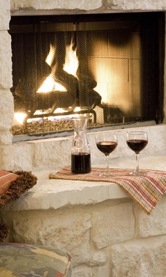 Image: Fireplace, fire, stone, striped pillows, decanter, wine glasses, books