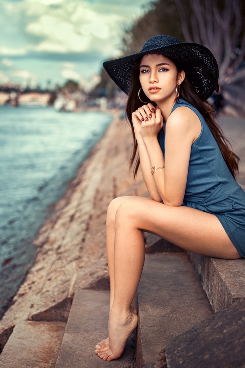 Image: Girl, brunette, sitting, legs, hat, dress, blue, waterfront, water, river, steps, barefoot